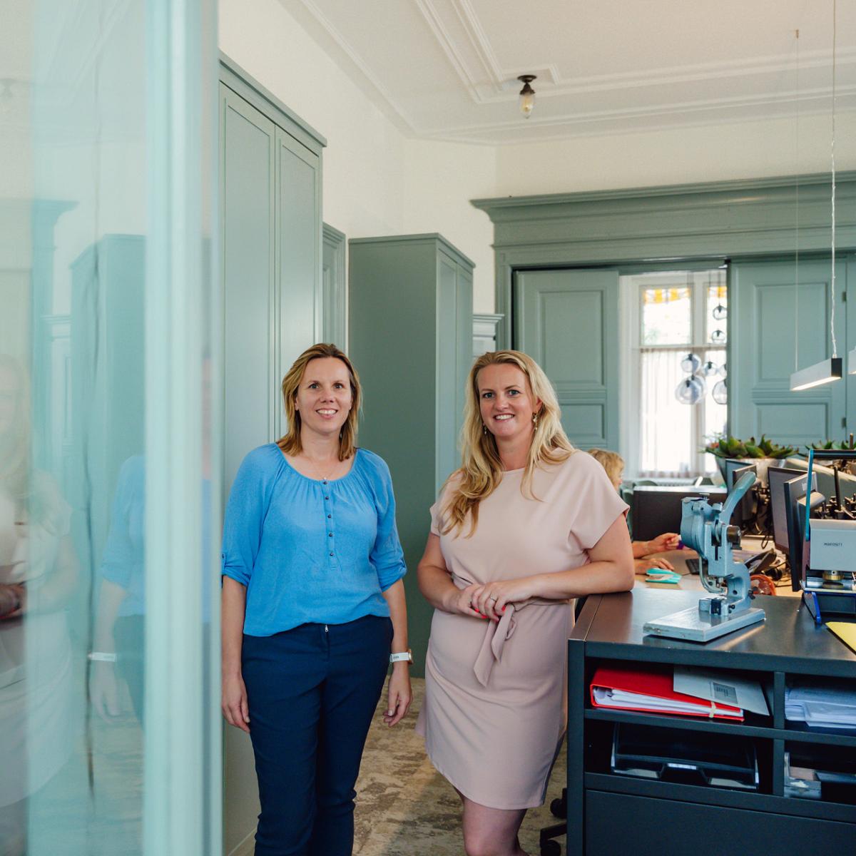 Twee vrouwen poseren glimlachend in het kantoor van Notariskantoor Voorhout.