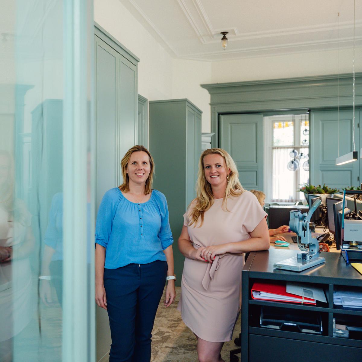 Twee vrouwen poseren glimlachend in het kantoor van Notariskantoor Voorhout.